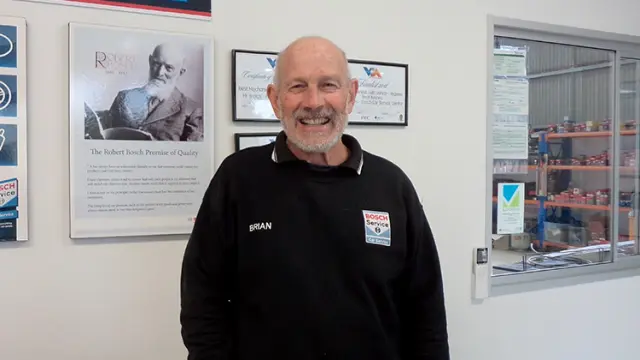 Smiling owner, Brian Canny, standing in the Bosch Car Service workshop, exuding confidence and professionalism in car repair.